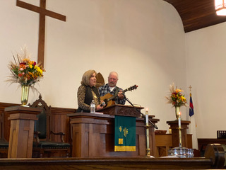 A picture of the woman playing guitar and singing on the mic